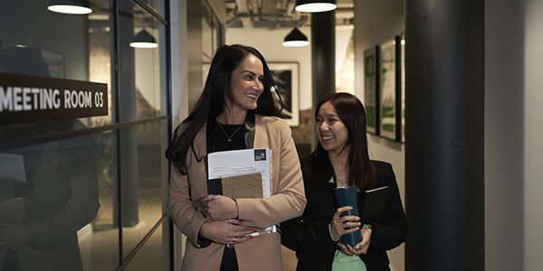 Two women walking down corridor in The Garment Factory 